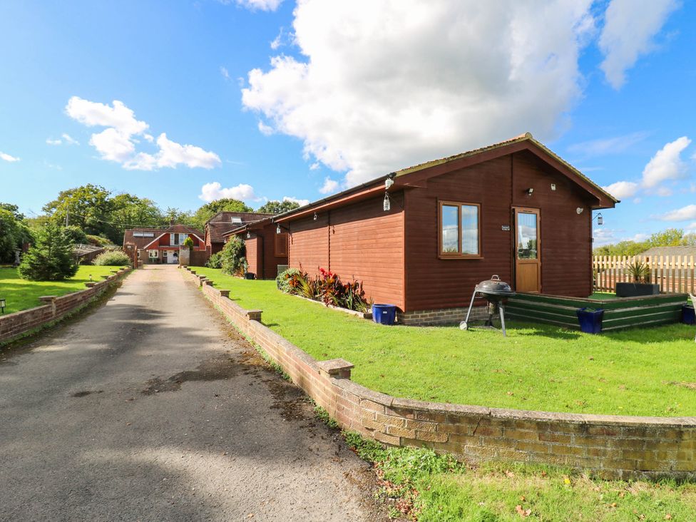 An outdoor view of a wooden lodge with a driveway at Elsie Lodge in Hastings