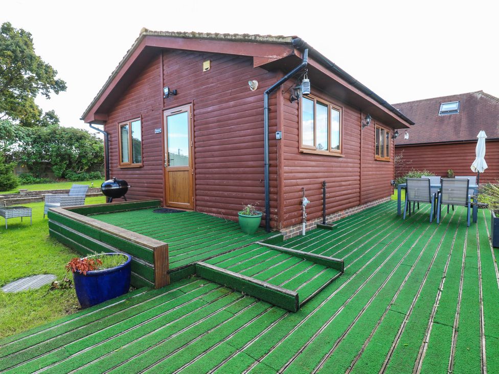 A garden with a wooden house and seating area at Rosie Lodge in Hastings