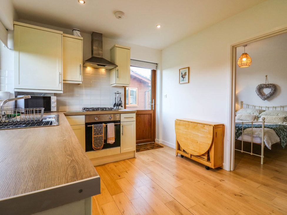 A kitchen with a stove and a microwave at Rosie Lodge in Hastings