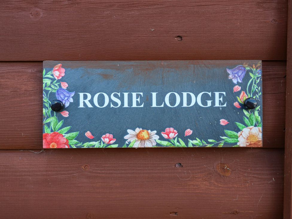 A sign that reads ROSIE LODGE with floral decorations at Rosie Lodge in Hastings