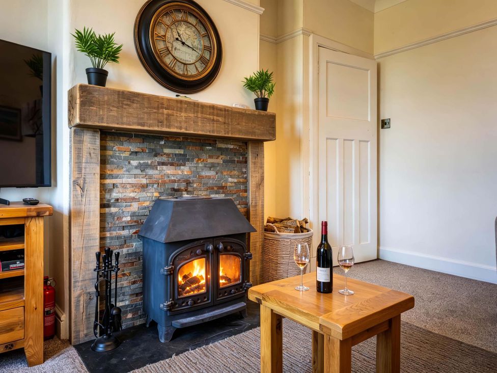 A living room with a fireplace and wooden table at Fereneze Lochranza, Isle Of Arran