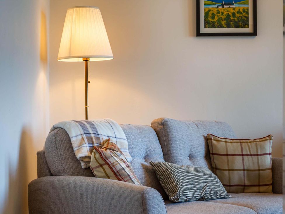 A living room with a sofa and lamp at Fereneze, Lochranza, Isle Of Arran