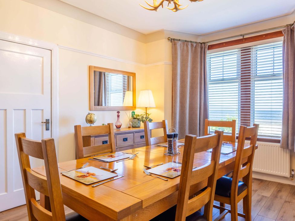 A dining room with a wooden table and chairs at Fereneze Lochranza, Isle Of Arran
