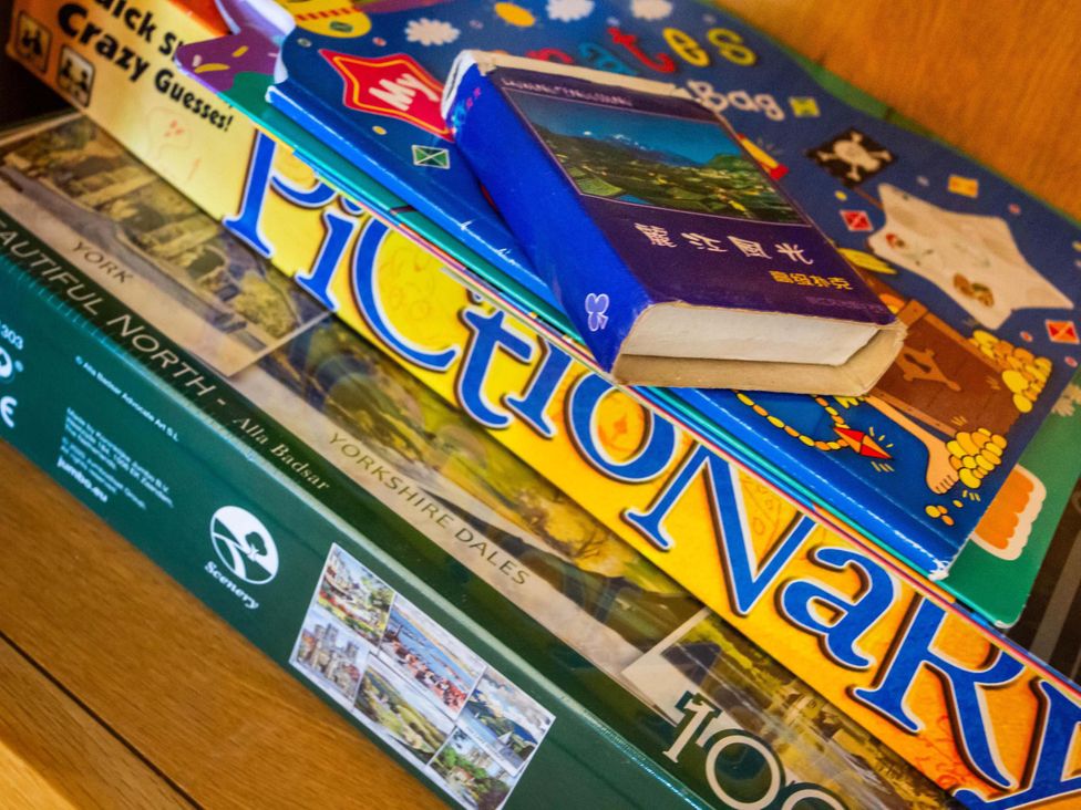 A stack of board games and books including Pictionary at Fereneze, Lochranza, Isle Of Arran