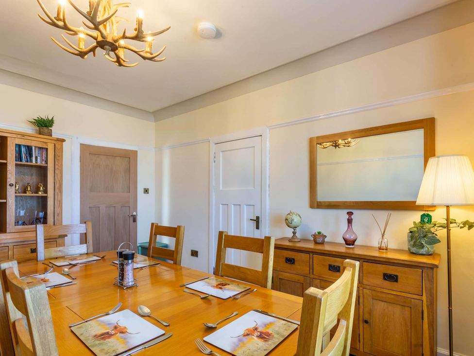 A dining room with a wooden table and chairs at Fereneze, Lochranza, Isle Of Arran
