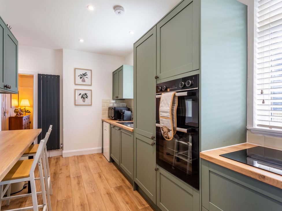 A kitchen with cabinets, appliances and seating area at Fereneze in Lochranza, Isle Of Arran