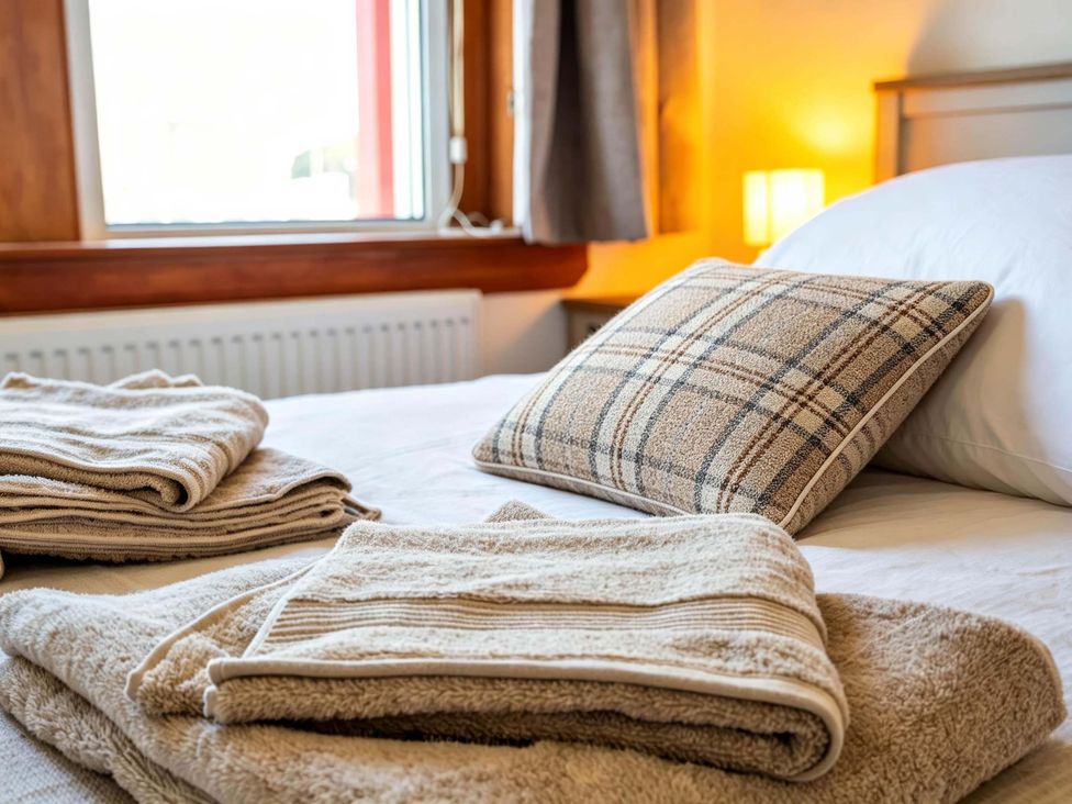 A bedroom with towels and a pillow on a bed at Fereneze Lochranza, Isle Of Arran