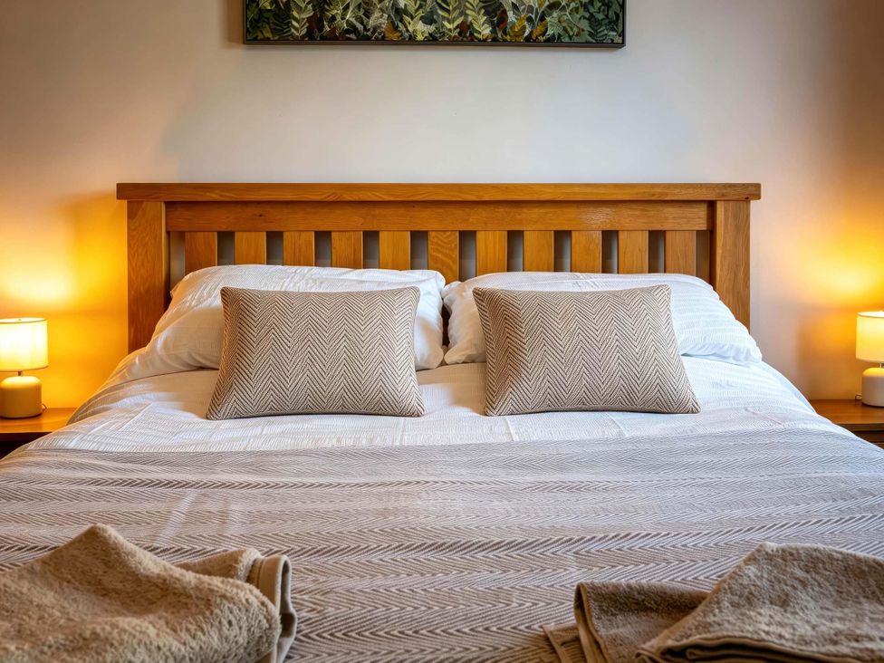 A bedroom with a wooden bed and decorative pillows at Fereneze Lochranza, Isle Of Arran