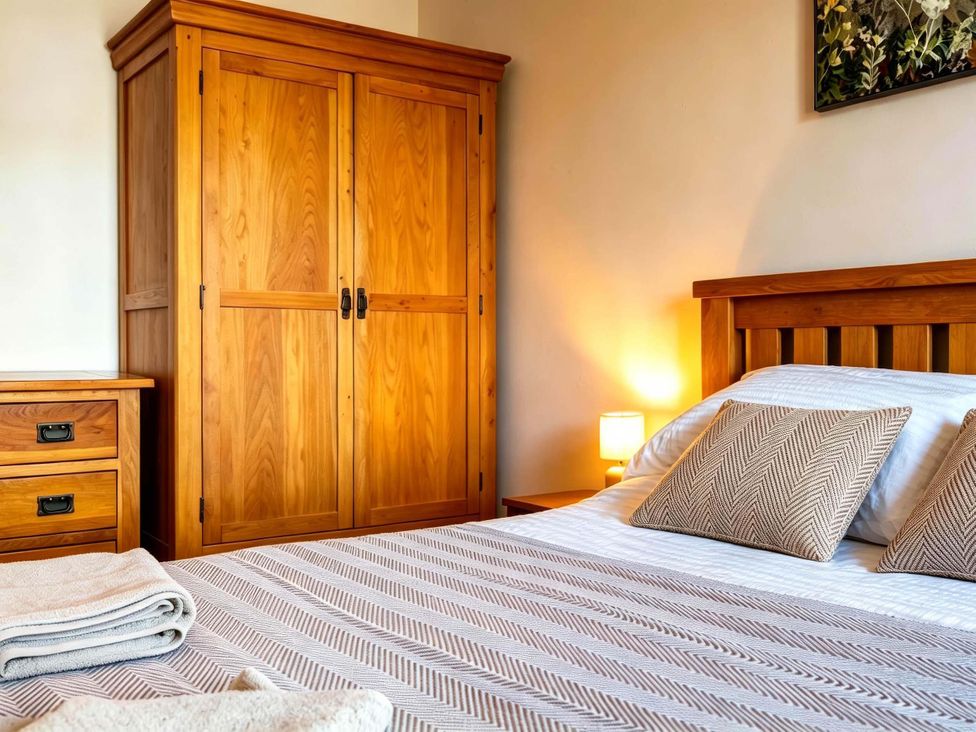 A bedroom with a bed and wardrobe at Fereneze Lochranza, Isle Of Arran