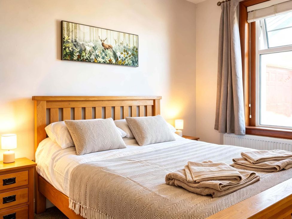 A bedroom with a wooden bed and bedside lamps at Fereneze, Lochranza, Isle Of Arran