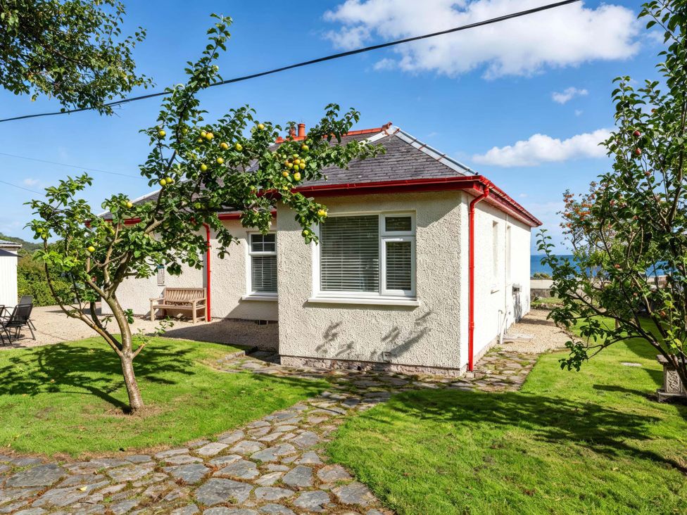 A house with trees and a bench outside at Fereneze, Lochranza, Isle Of Arran