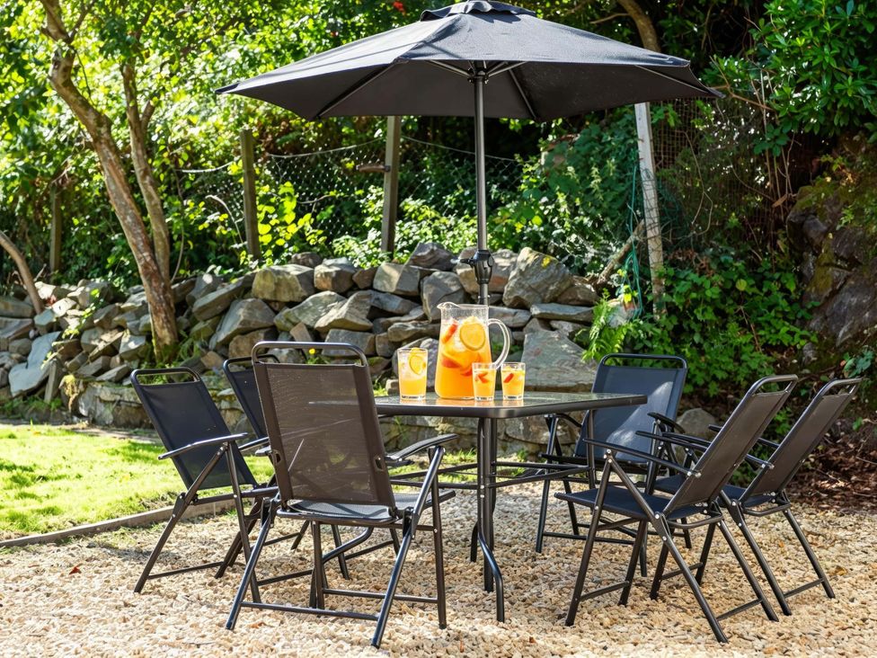 A garden with a table and chairs under an umbrella at Fereneze Lochranza, Isle Of Arran