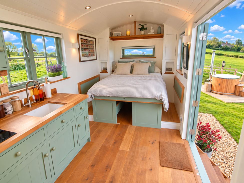 A bedroom with a bed and kitchen area at Oak Hut Bishops Castle