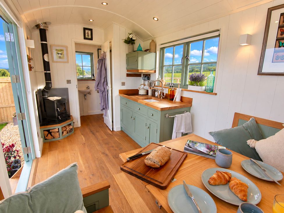 A kitchen with stove, sink, cabinets, and dining table at Oak Hut in Bishops Castle