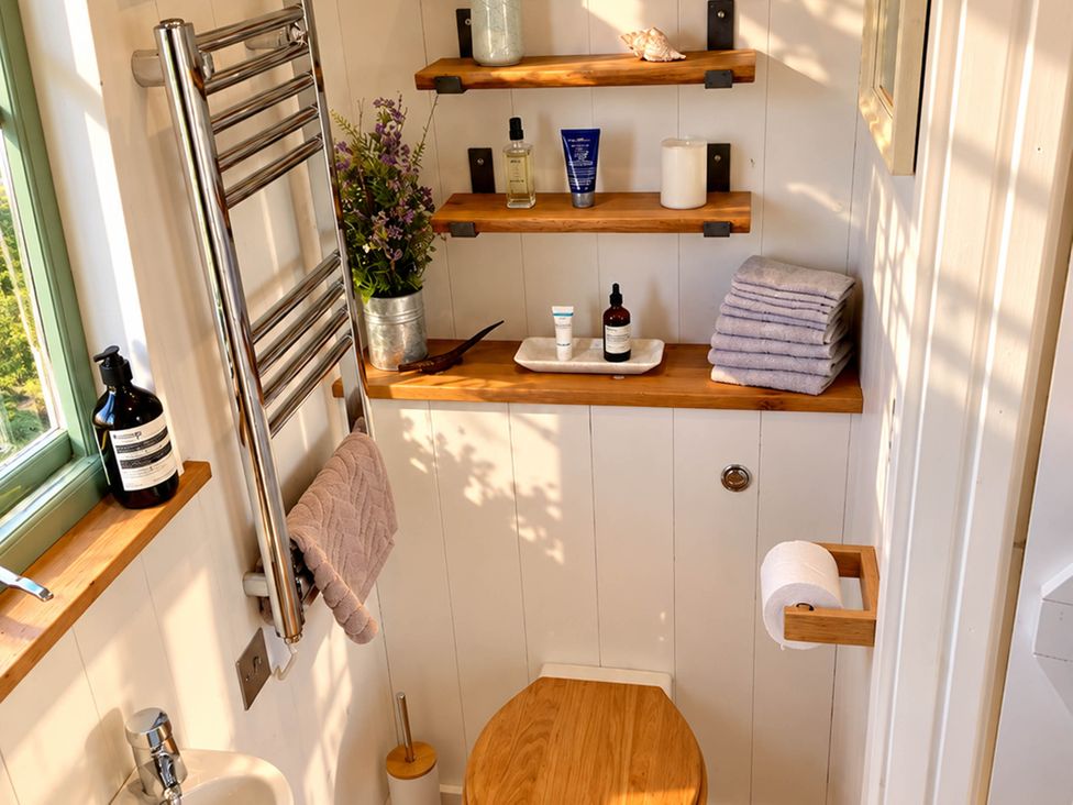 A bathroom with a toilet and shelves at Oak Hut in Bishops Castle