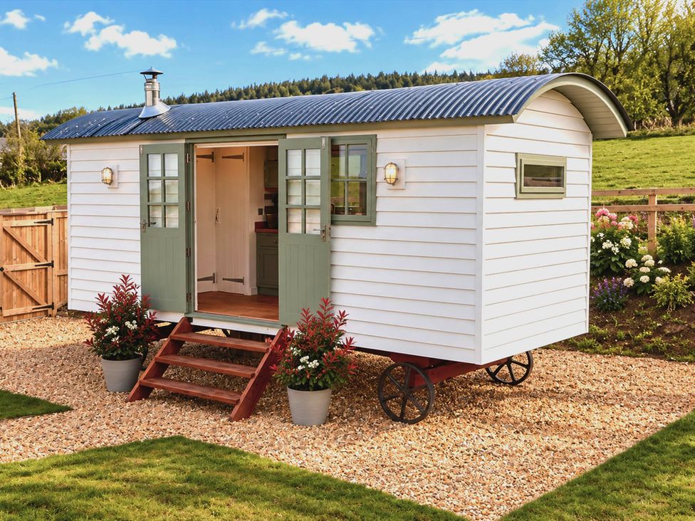 A shepherd's hut with green doors and steps at Oak Hut in Bishops Castle