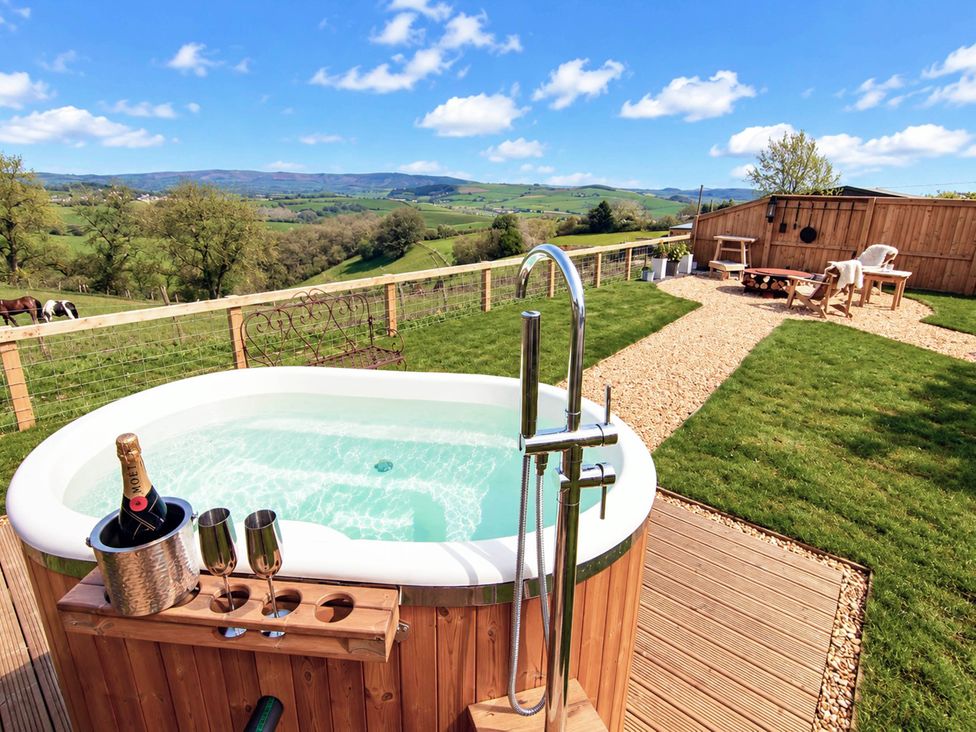 A hot tub with champagne and glasses in the garden at Oak Hut in Bishops Castle