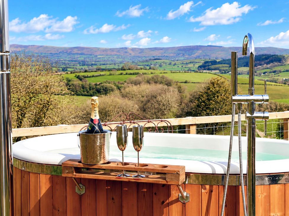 A hot tub with champagne and glasses at Oak Hut in Bishops Castle