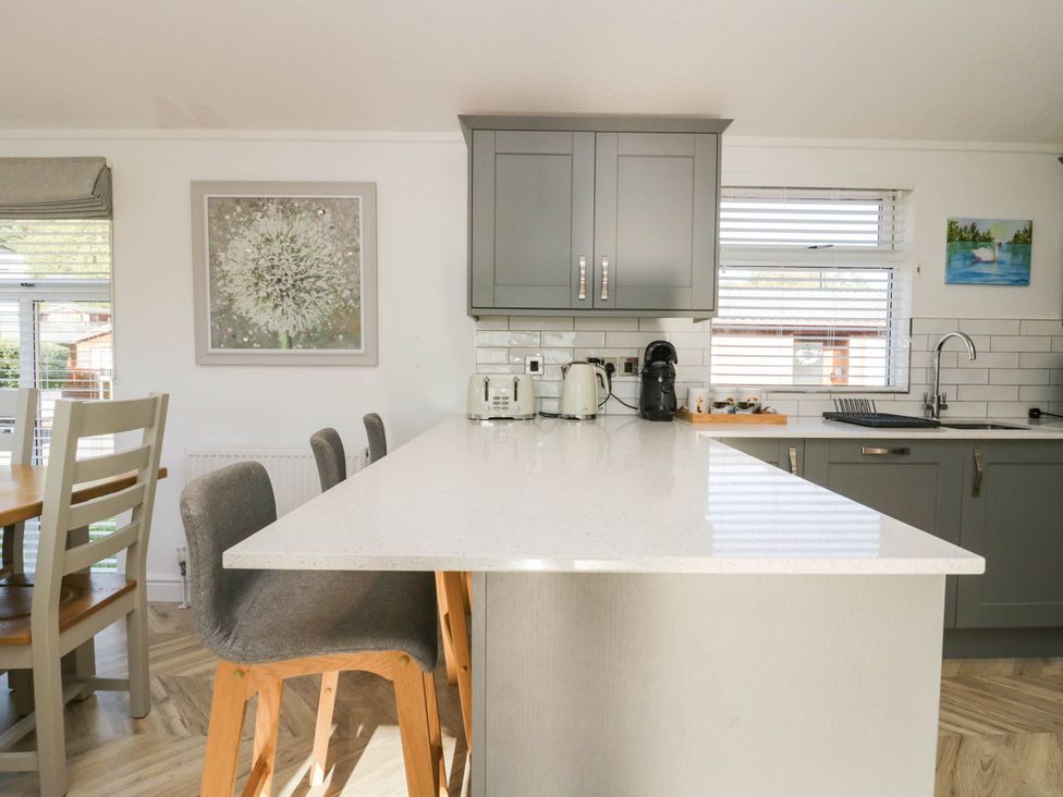 A kitchen with cabinets, island, sink, and dining table at Thirlmere Scar in Troutbeck Bridge
