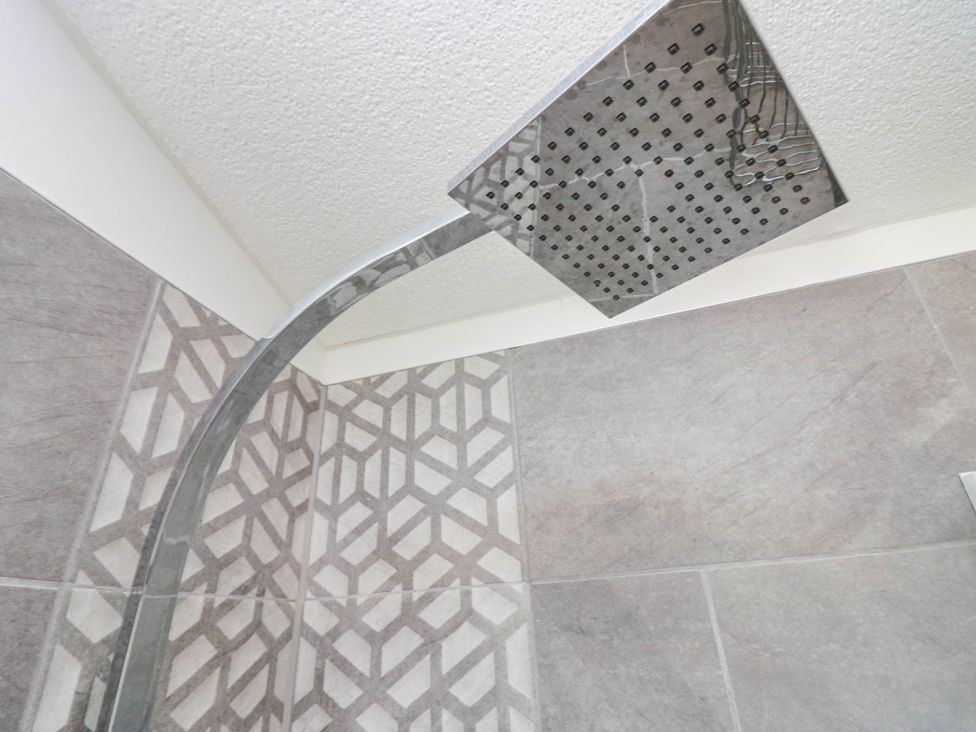 A shower head with tiled walls and floor at Thirlmere Scar in Windermere