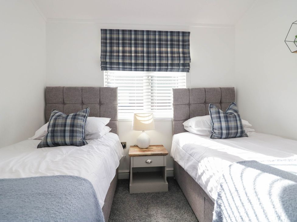 A bedroom with twin beds and a nightstand at Thirlmere Scar in Windermere