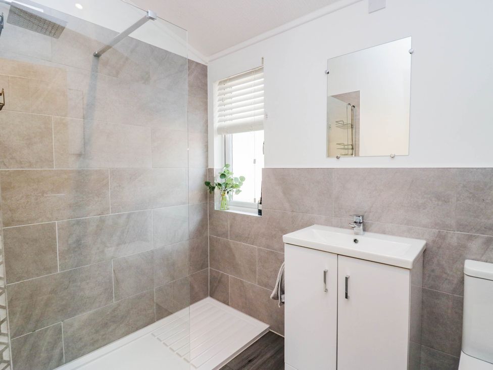 A bathroom with a shower, sink, and toilet at Thirlmere Scar in Windermere
