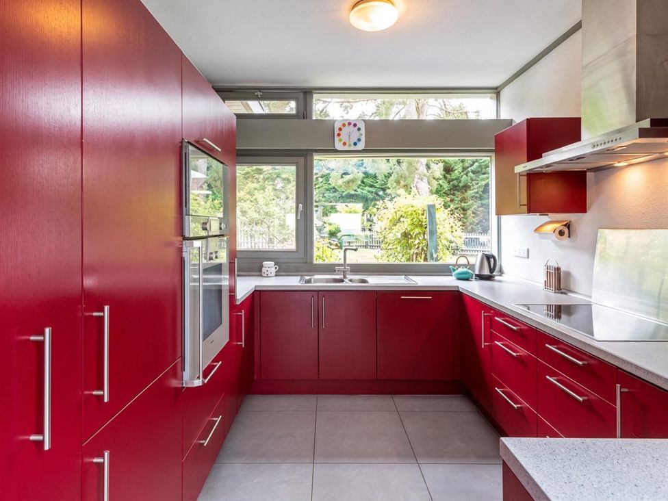 A kitchen with red cabinets and window at Two Hoots Littleworth