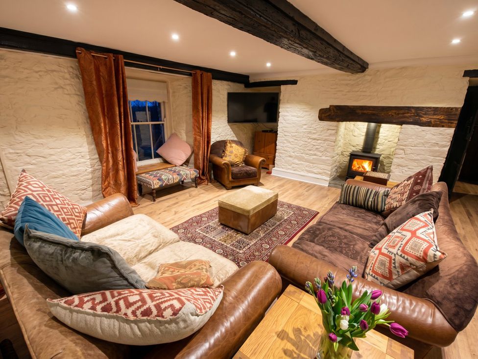 A living room with a sofa, chair, coffee table, and television at Tynewydd Farmhouse