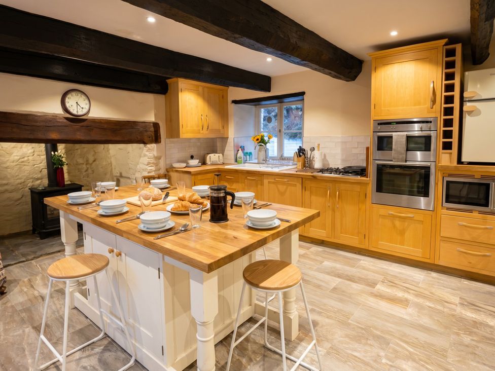 A kitchen with countertop, stove, oven, and dining plates at Tynewydd Farmhouse
