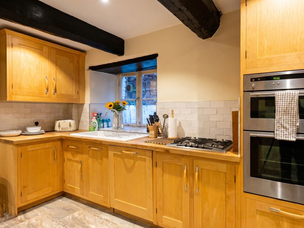 A kitchen with wooden cabinets and appliances at Tynewydd Farmhouse