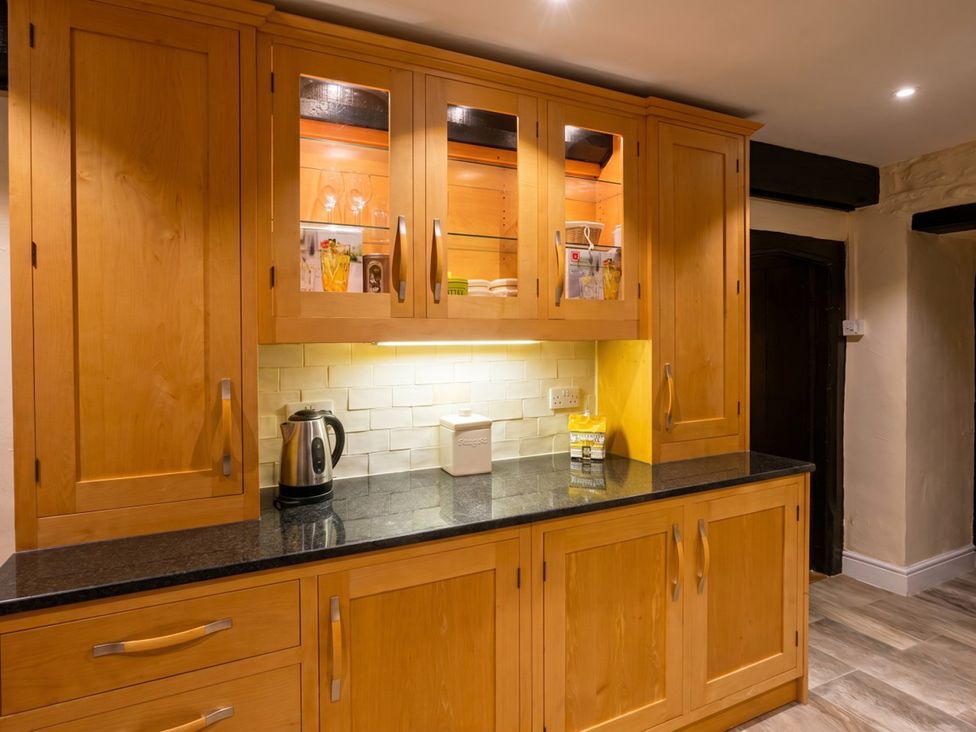 A kitchen with wooden cabinets and countertop at Tynewydd Farmhouse