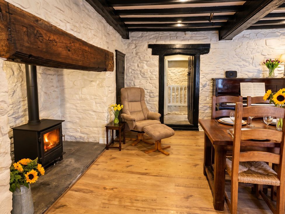 A living room with a stove and dining table at Tynewydd Farmhouse 