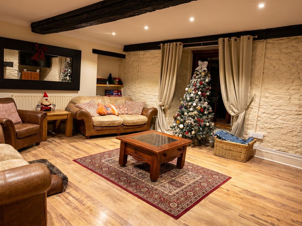A living room with a Christmas tree and seating at Tynewydd Farmhouse