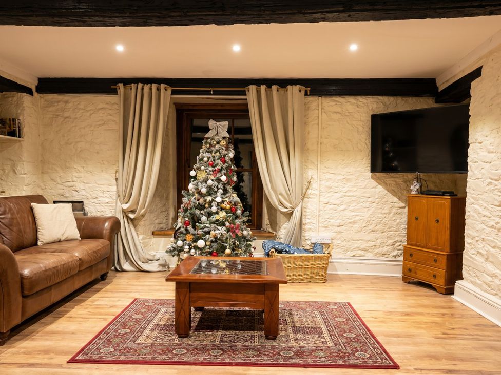 A living room with a Christmas tree and a coffee table at Tynewydd Farmhouse