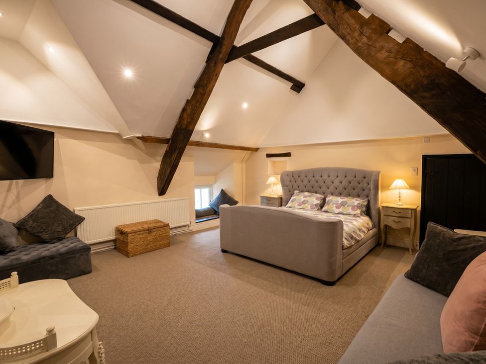 A bedroom with a bed and sofa at Tynewydd Farmhouse