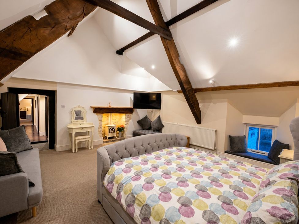 A bedroom with a bed and sofa at Tynewydd Farmhouse