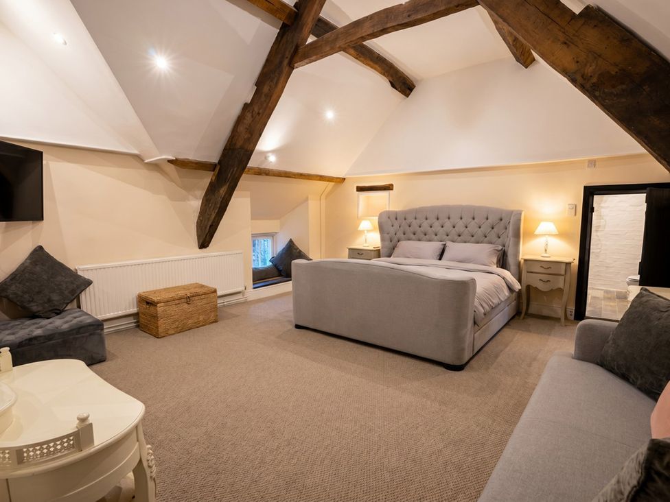 A bedroom with a bed and sofa at Tynewydd Farmhouse