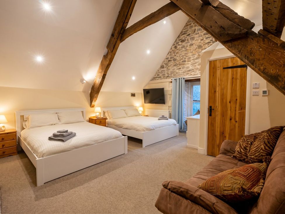 A bedroom with two beds and a sofa at Tynewydd Farmhouse