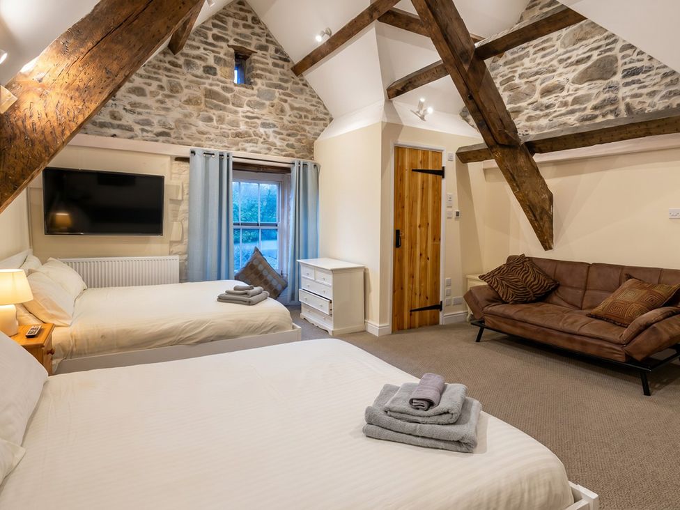 A bedroom with two beds and a sofa at Tynewydd Farmhouse
