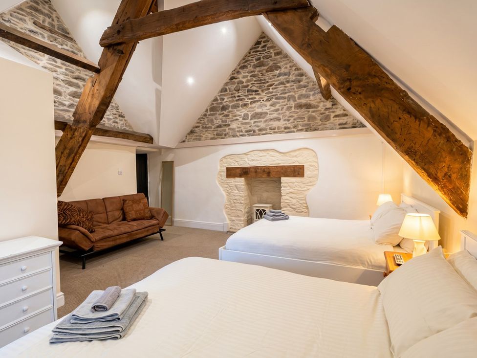 A bedroom with two beds and a sofa at Tynewydd Farmhouse