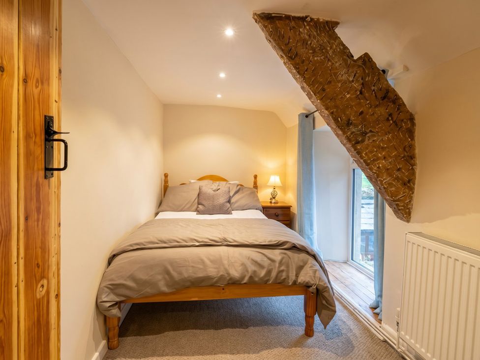 A bedroom with a bed and a lamp at Tynewydd Farmhouse