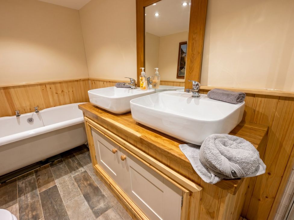 A bathroom with wash basins and a bathtub at Tynewydd Farmhouse