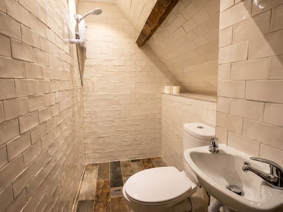 A bathroom with shower, toilet, and sink at Tynewydd Farmhouse