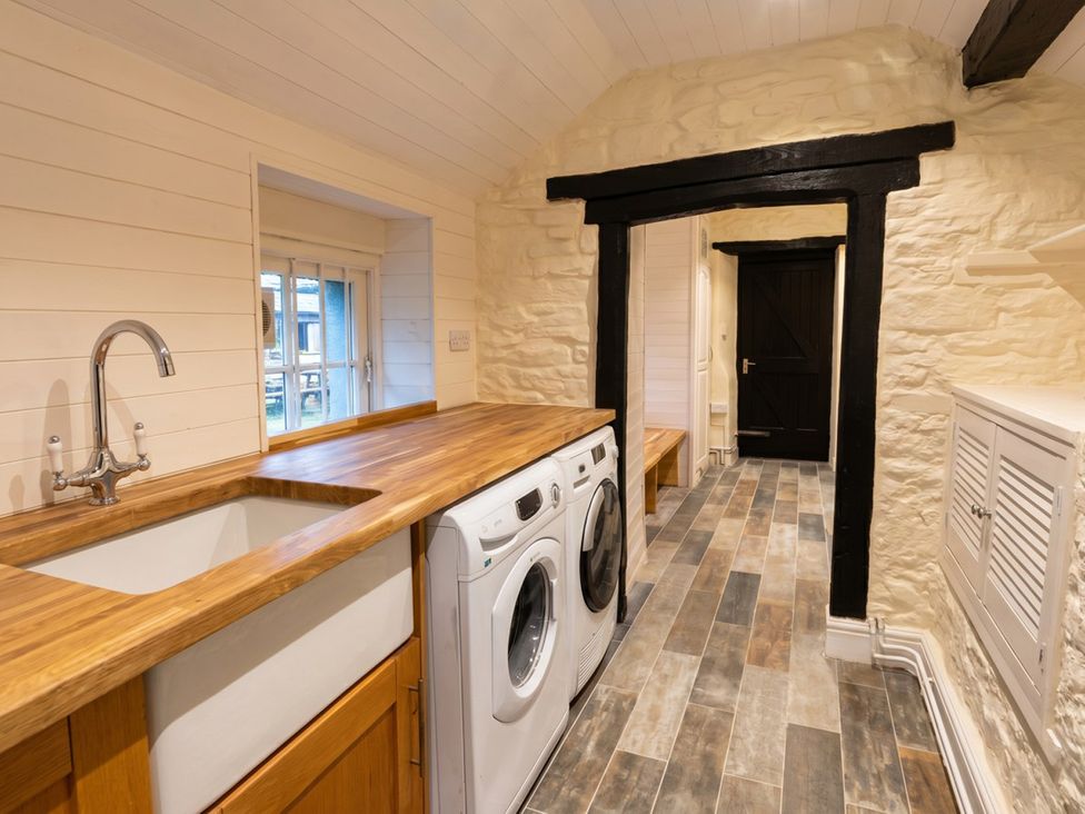 A laundry room with a sink and washing machine at Tynewydd Farmhouse