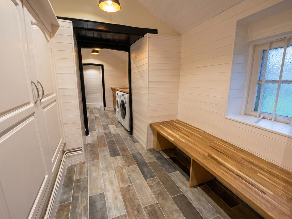 A utility room with a washer and bench at Tynewydd Farmhouse