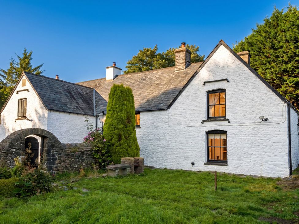 An outdoor view of a white house with windows and garden at Tynewydd Farmhouse 
