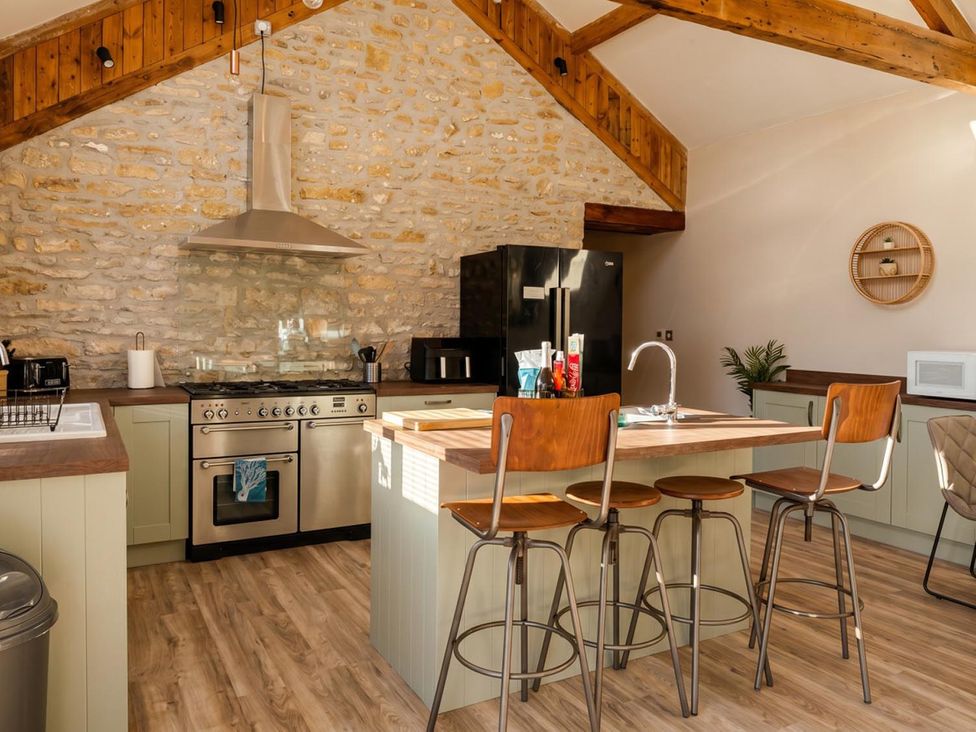 A kitchen with stove, refrigerator, and barstools at The Old Barn in Manchester