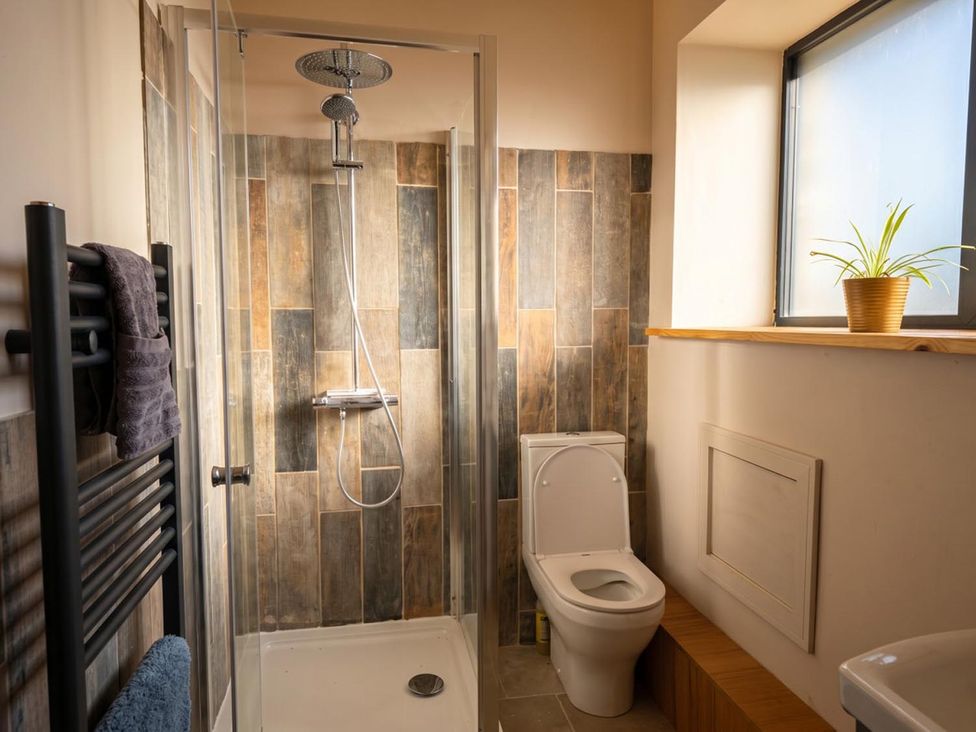 A bathroom with a shower, toilet, and towel radiator at The Old Barn in Manchester