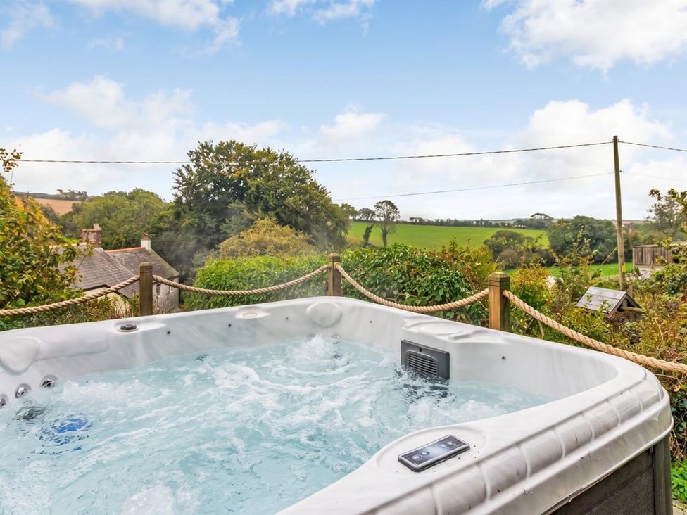 A hot tub with water and greenery at an outdoor location