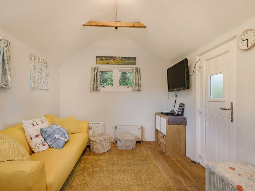 A snug with a yellow sofa, television, and table at The Old Barn in Manchester